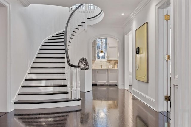 entryway with ornamental molding and hardwood / wood-style floors