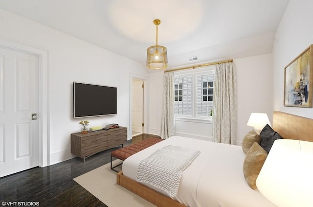 bedroom with a raised ceiling and dark hardwood / wood-style flooring