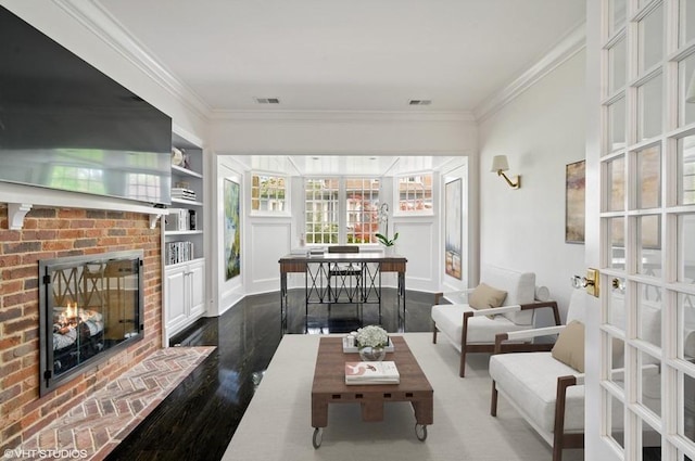 living room featuring built in features, ornamental molding, dark hardwood / wood-style flooring, and a brick fireplace