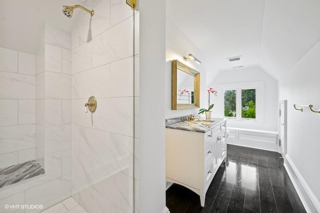 bathroom with vaulted ceiling, tiled shower, hardwood / wood-style floors, and vanity