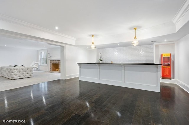 interior space with dark wood-type flooring, ornamental molding, a fireplace, and hanging light fixtures