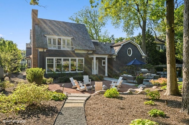 rear view of house with a patio area and an outdoor living space with a fire pit