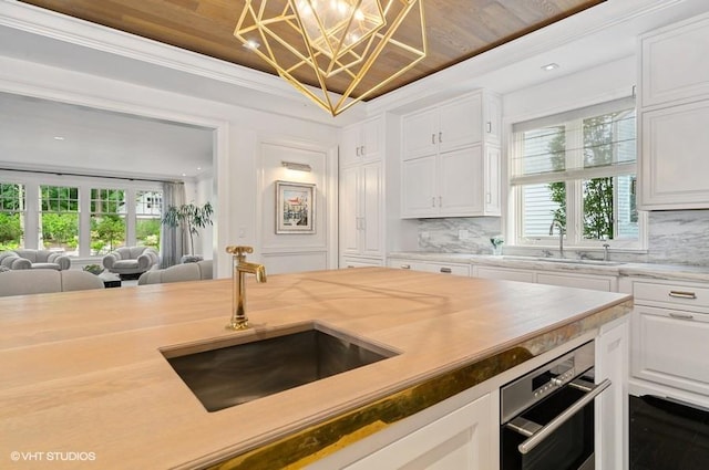 kitchen with backsplash, a wealth of natural light, sink, and white cabinets