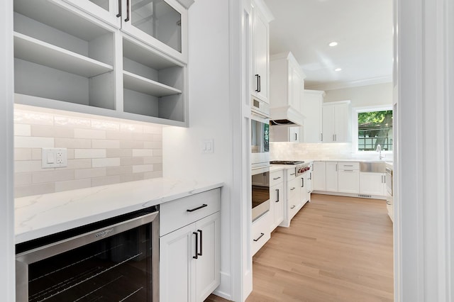 kitchen with white cabinets, beverage cooler, tasteful backsplash, light stone counters, and light hardwood / wood-style flooring