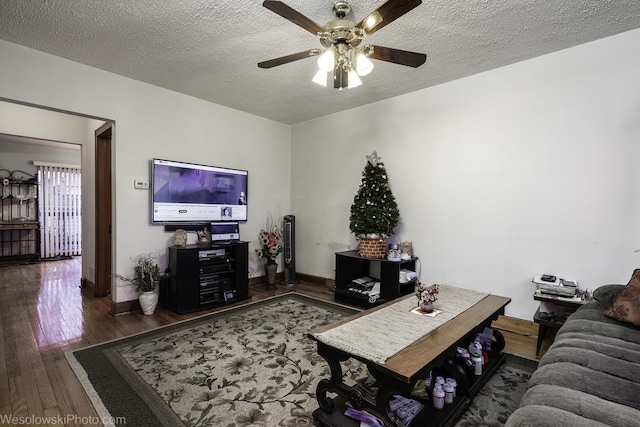 living room with ceiling fan, a textured ceiling, and dark hardwood / wood-style floors