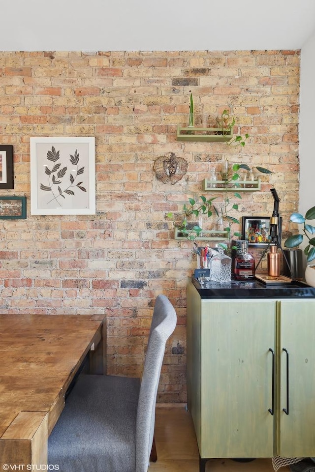 interior space featuring green cabinetry, butcher block counters, and brick wall