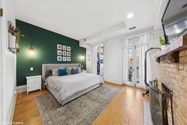 bedroom featuring light hardwood / wood-style flooring, access to outside, and a fireplace