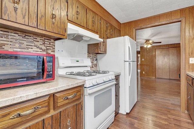 kitchen with wooden walls, ceiling fan, dark hardwood / wood-style flooring, and gas range gas stove