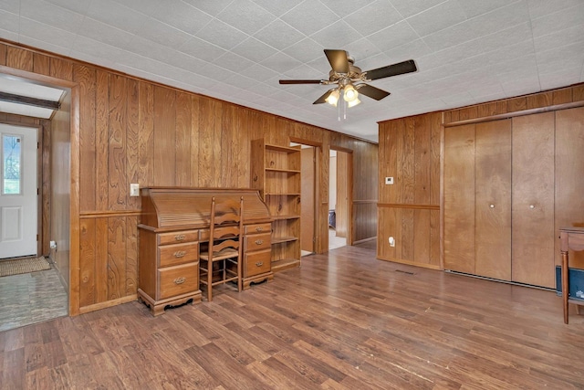 office space with hardwood / wood-style floors, wooden walls, and ceiling fan