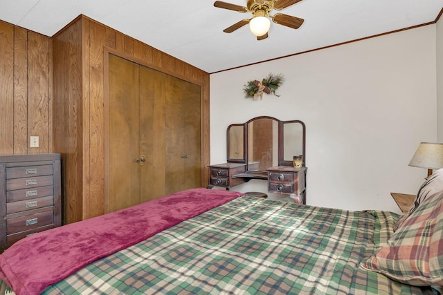 bedroom with ceiling fan, ornamental molding, wooden walls, and a closet