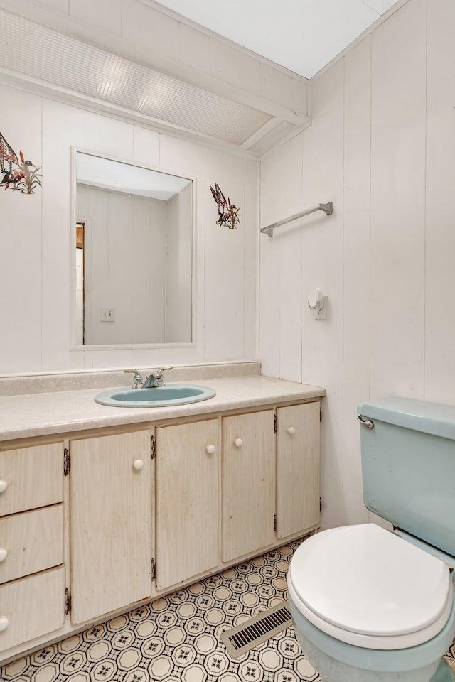 bathroom with wooden walls, vanity, and toilet