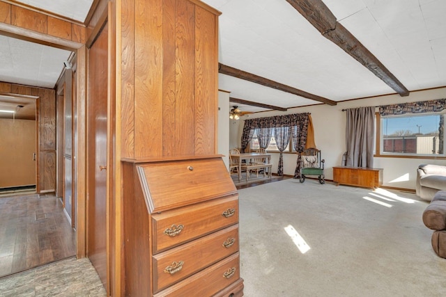 interior space with beamed ceiling, a baseboard radiator, a healthy amount of sunlight, and wooden walls