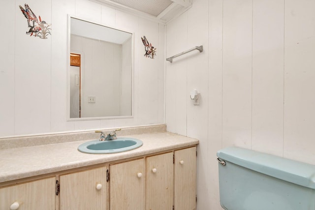 bathroom featuring vanity, toilet, and wood walls