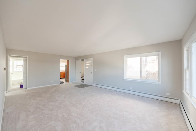 carpeted spare room with baseboard heating and plenty of natural light