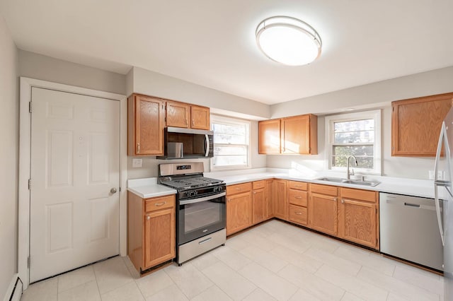 kitchen featuring a healthy amount of sunlight, baseboard heating, sink, and stainless steel appliances