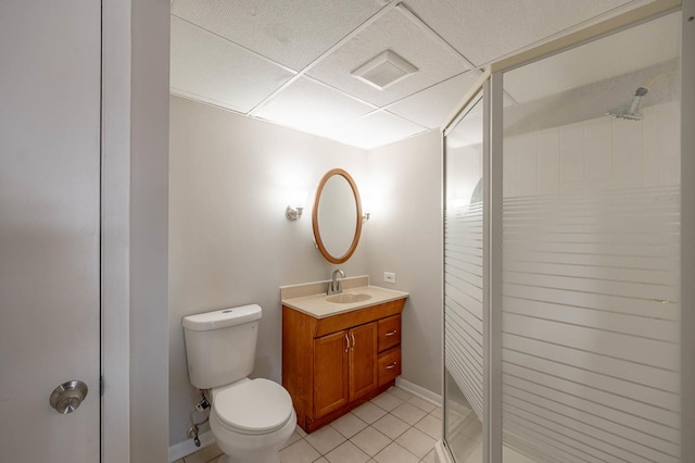 bathroom featuring toilet, a shower with door, a paneled ceiling, tile patterned flooring, and vanity