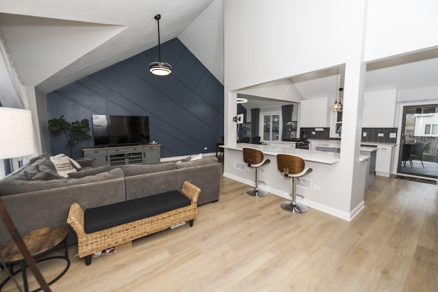 living room with high vaulted ceiling and light hardwood / wood-style flooring