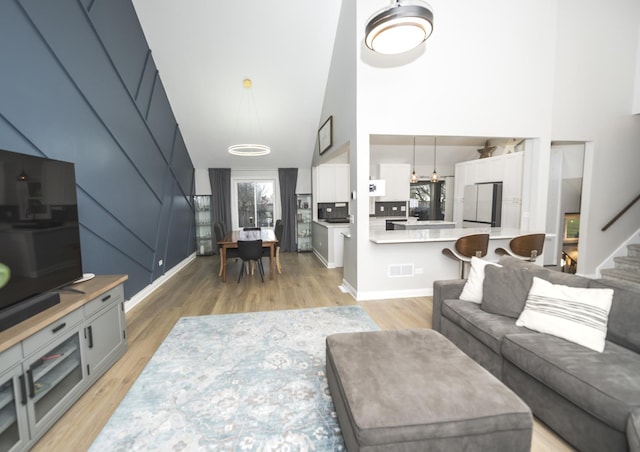 living room featuring light hardwood / wood-style floors and high vaulted ceiling