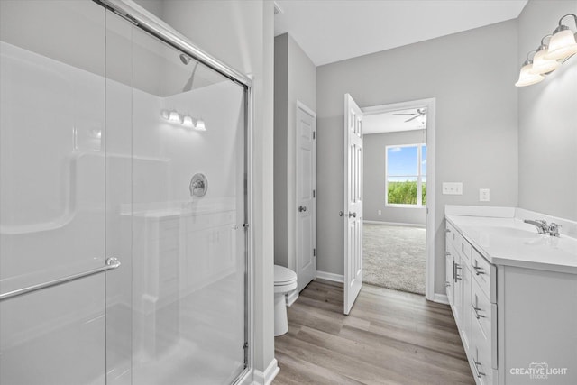 bathroom featuring toilet, hardwood / wood-style flooring, walk in shower, ceiling fan, and vanity