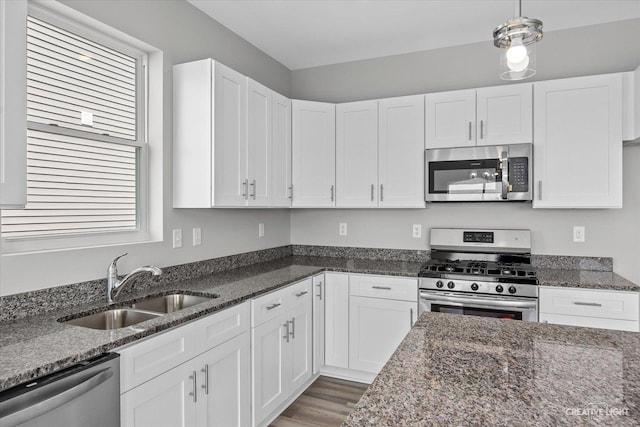 kitchen with decorative light fixtures, stainless steel appliances, dark stone countertops, and white cabinets