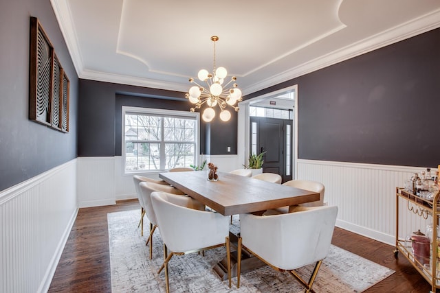 dining space with crown molding, dark hardwood / wood-style floors, and an inviting chandelier