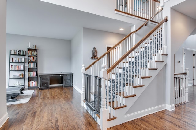 staircase with hardwood / wood-style flooring and a towering ceiling