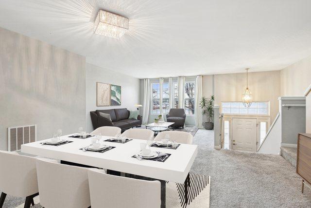 carpeted dining area with a chandelier