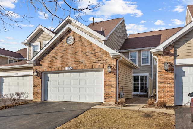 view of front facade with a garage, driveway, and brick siding