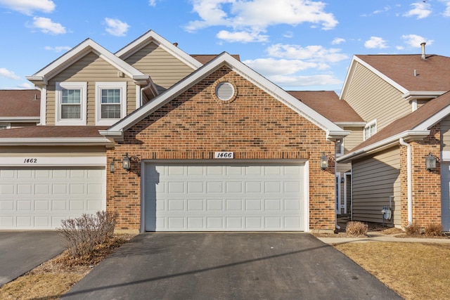 traditional-style home featuring aphalt driveway and brick siding