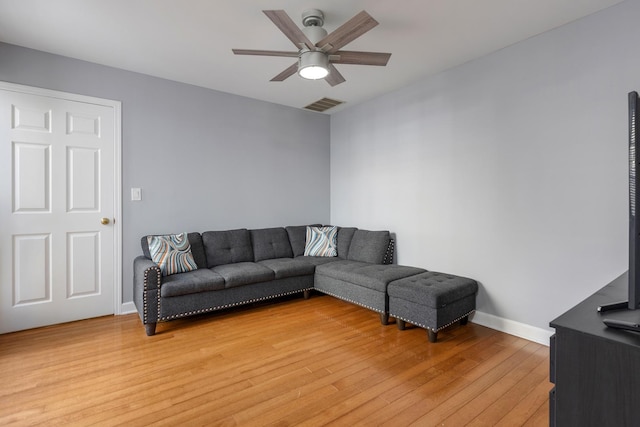 living room featuring light wood-type flooring, ceiling fan, visible vents, and baseboards