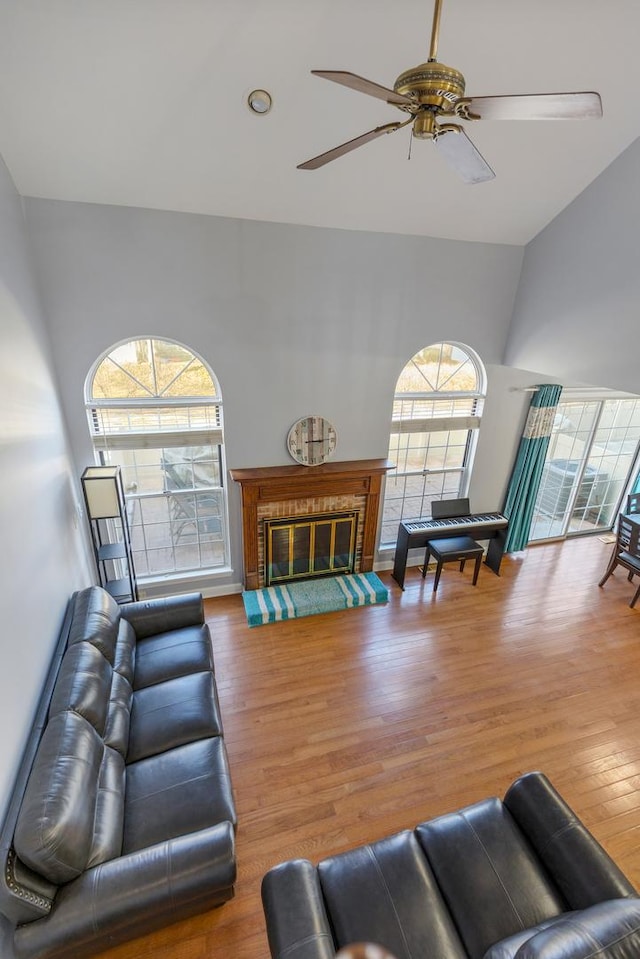 living area featuring ceiling fan, wood finished floors, and a glass covered fireplace