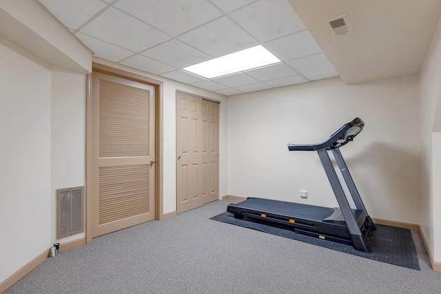 workout area featuring a paneled ceiling, carpet, visible vents, and baseboards