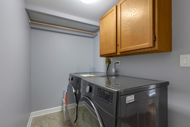 washroom featuring baseboards, cabinet space, and washing machine and clothes dryer