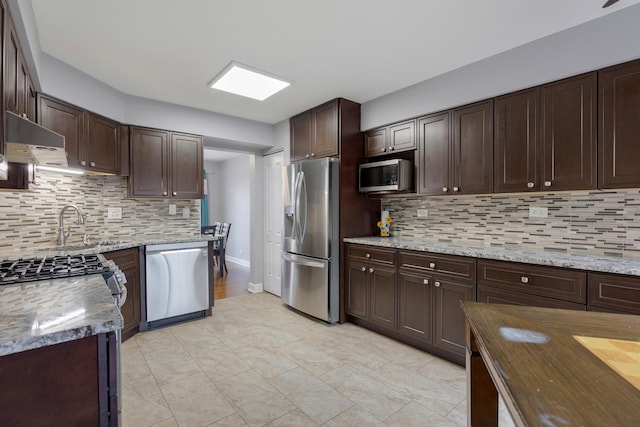 kitchen with appliances with stainless steel finishes, backsplash, under cabinet range hood, and dark brown cabinets