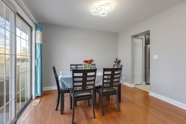 dining space featuring baseboards, visible vents, and light wood finished floors