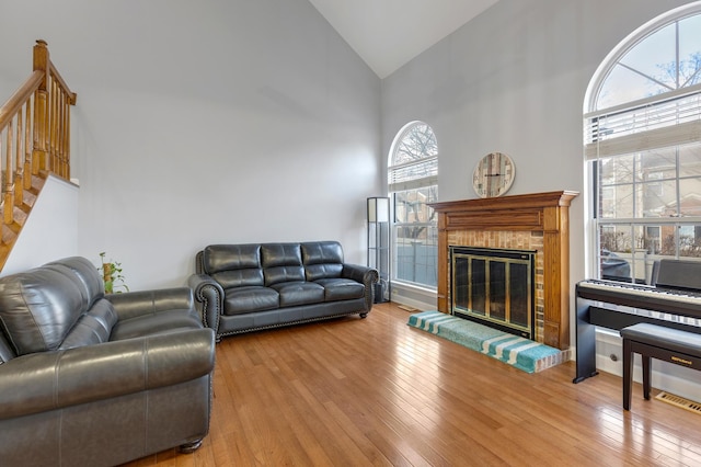 living room featuring stairway, a fireplace, high vaulted ceiling, and hardwood / wood-style floors