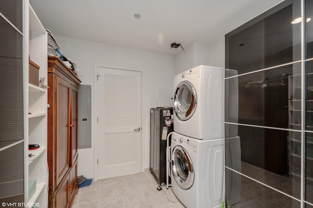 laundry area featuring stacked washer / drying machine and electric panel