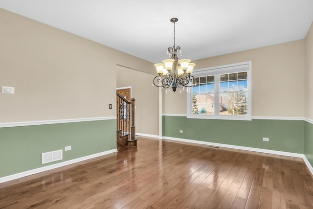 spare room featuring hardwood / wood-style floors and a notable chandelier