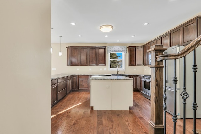 kitchen featuring high end stainless steel range, pendant lighting, dark hardwood / wood-style floors, and light stone countertops