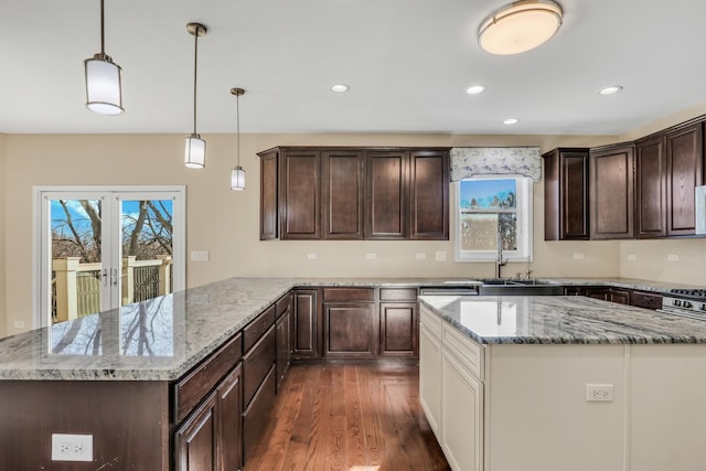 kitchen with sink, a healthy amount of sunlight, decorative light fixtures, and light stone counters