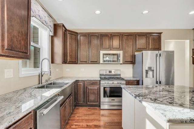 kitchen with stainless steel appliances, a healthy amount of sunlight, and light stone counters