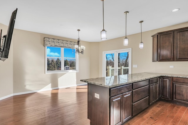 kitchen with hanging light fixtures, dark hardwood / wood-style floors, a wealth of natural light, and light stone countertops