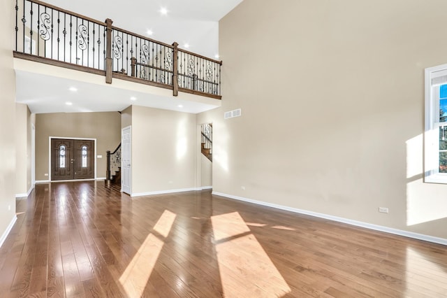 unfurnished living room featuring a high ceiling and wood-type flooring