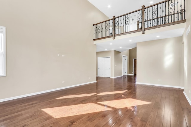 unfurnished living room with a high ceiling and dark hardwood / wood-style flooring