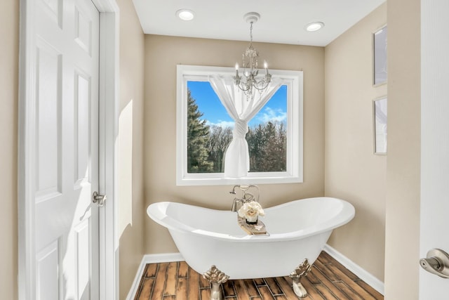 bathroom with a notable chandelier, hardwood / wood-style floors, and a bathing tub