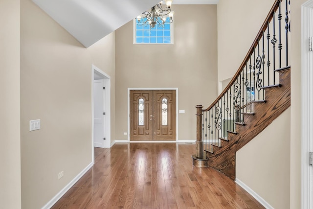 foyer featuring a notable chandelier, a towering ceiling, and wood-type flooring