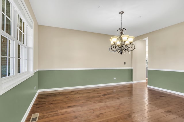 unfurnished room with dark hardwood / wood-style flooring, plenty of natural light, and a chandelier