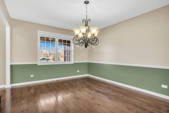 unfurnished room featuring dark hardwood / wood-style flooring and an inviting chandelier