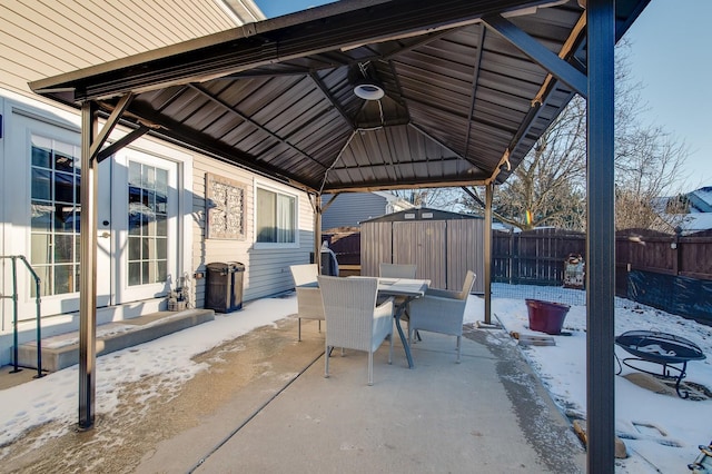 snow covered patio with a gazebo and a shed