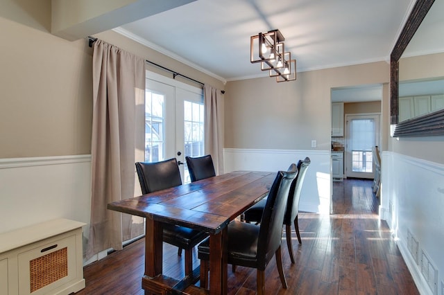 dining area with an inviting chandelier, french doors, crown molding, and dark hardwood / wood-style floors